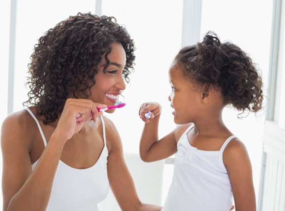 Mom and daughter brushing their teeth together