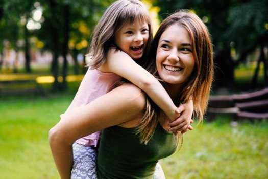 Smiling woman giving piggy-back ride to laughing little girl