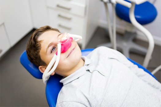 Little boy with gas mask over nose in dental chair