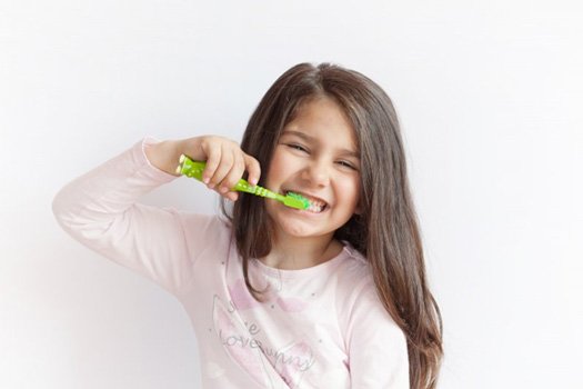 Girl smiling and brushing her teeth on a white background