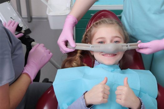 Girl giving two thumbs-up while receiving nitrous oxide sedation