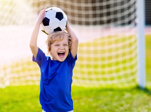 child smiling while holding soccer ball 