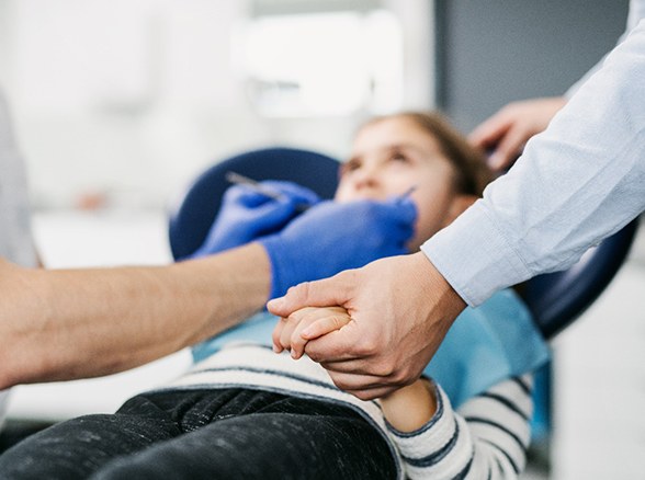 Parent holding child's hand during dental treatment