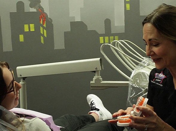 Dentist talking to child during dental checkup and teeth cleaning visit