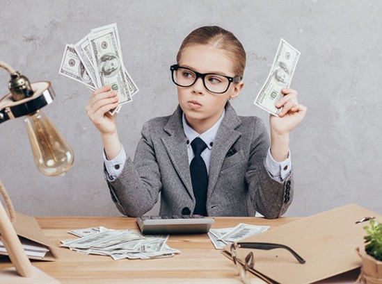 Child in a suit holding money and looking confused 