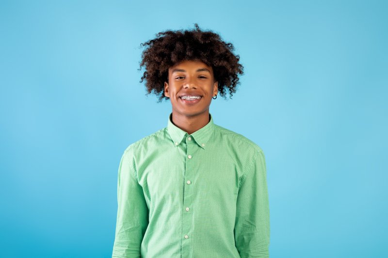 A teenager smiling after seeing his pediatric dentist