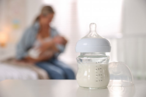 A bottle of milk sitting on a table in the foreground with mother and child in the background