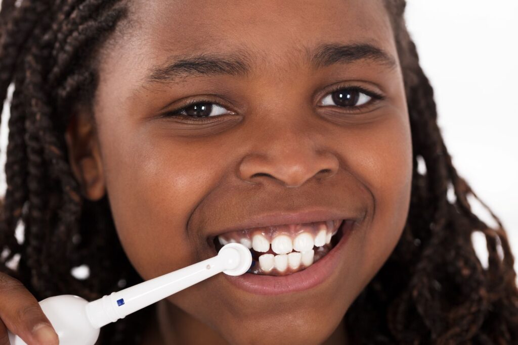 A little girl using an electric toothbrush