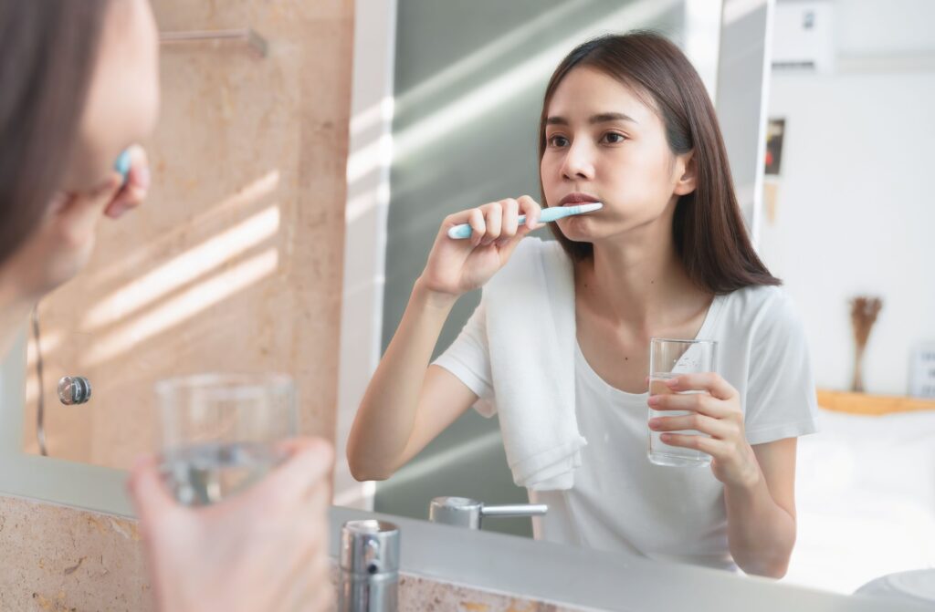 Teen brushing teeth at bathroom mirror